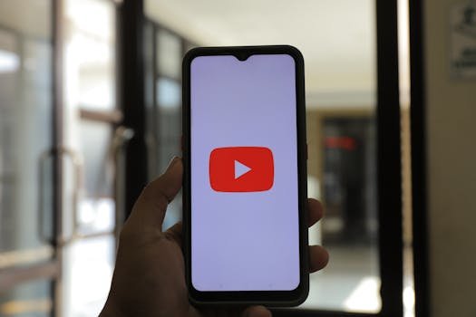 pexels-photo-13883889-13883889 A hand holding a smartphone displaying the YouTube app indoors.
