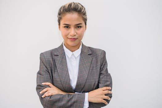 pexels-photo-4964999-4964999 Portrait of a confident Asian woman in a plaid blazer with arms crossed, smiling and posing.